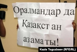 Қазақстандағы оралмандар жағдайына арналған баспасөз жиынына қатысушы ұстап тұрған жазу. Алматы, 4 қазан 2011 жыл. (Көрнекі сурет)